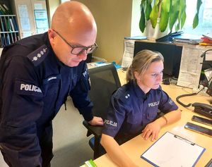 Policjant i policjantka patrzą w monitor komputera.