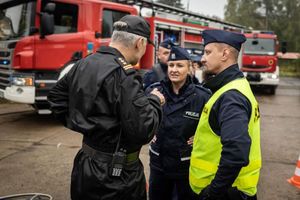 Policjantka i policjant rozmawiają ze strażakiem.