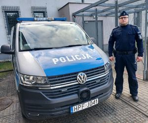 Policjant stoi przy radiowozie.