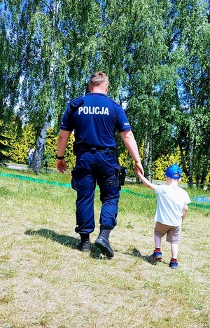 Policjant idzie za rękę z małym chłopcem.