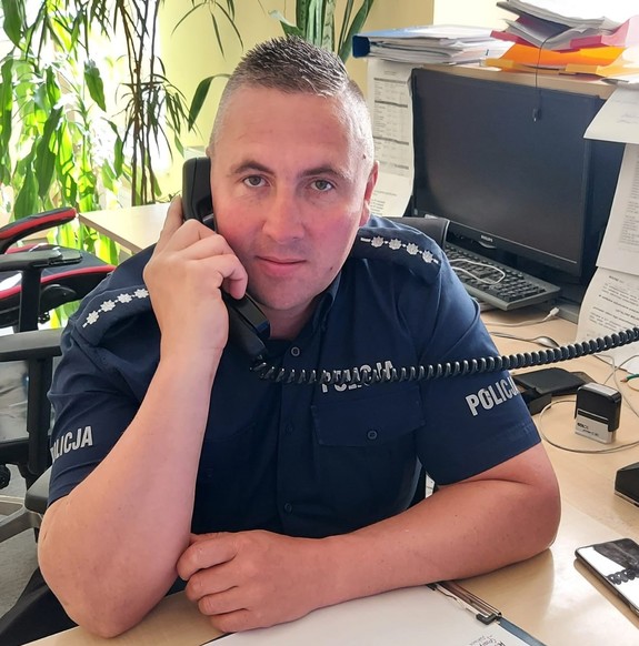 Policjant w mundurze rozmawia przez telefon.