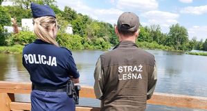 Policjantka i strażnik leśny patrolują miejsca przy zbiornikach wodnych.