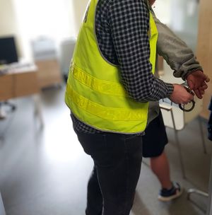 Policjant zdejmuje kajdanki zatrzymanemu.