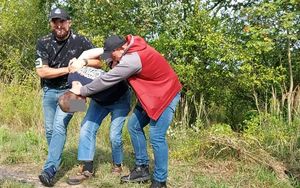 Dwóch policjantów prowadzi zatrzymanego mężczyznę.