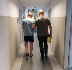 Policjant prowadzi zatrzymanego mężczyznę.