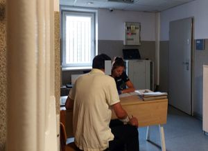 Zatrzymany mężczyzn siedzi przed policjantką.