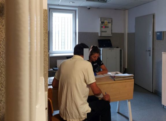 Zatrzymany mężczyzn siedzi przed policjantką.