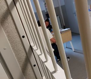 Za okratowanymi drzwiami siedzi policjantka z zatrzymanym mężczyzną.