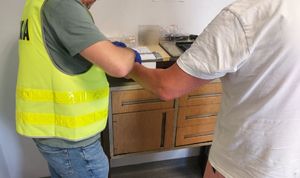 Policjant pobiera odciski palców zatrzymanemu mężczyźnie.