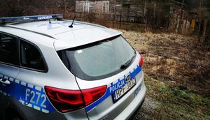 Radiowóz stoijący przed opuszczonym budynkiem.