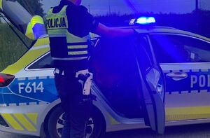 Policjant stoi przy radiowozie.
