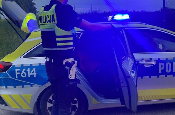 Policjant stoi przy radiowozie.