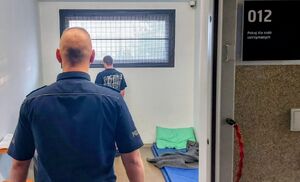 Policjant stoi przy zatrzymanym mężczyźnie.