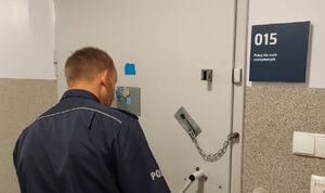 Policjant wchodzi do pomieszczenia gdzie jest zatrzymany policjant.