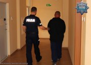 umundurowany policjant prowadzi korytarzem zatrzymanego mężczyznę