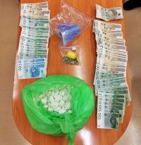 duża ilość narkotyków w postaci białego proszku w torbie foliowej i pieniądze rozłożone na blacie stołu