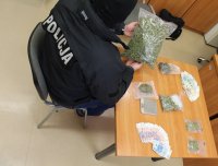 Policjant z zabezpieczonymi narkotykami, pieniędzmi i wagą.