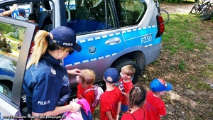 policjanci w trakcie działań profilaktycznych z dziećmi na tle radiowozu