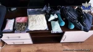 zabezpieczone przez policjantów tabletki ekstazy i marihuana w przeźroczystych torbach rozłożone na blacie komody