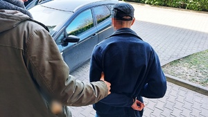 policjanci prowadzą zatrzymanego mężczyznę do radiowozu