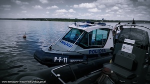 policyjna łódź motorowa zacumowana obok innej łodzi w tle akwen wodny