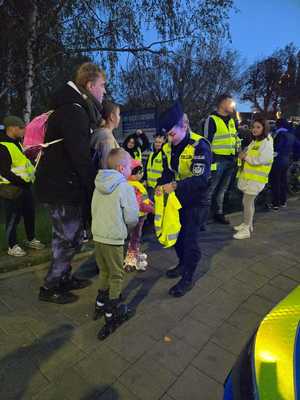 Policjantka rozdaje dzieciom odblaski