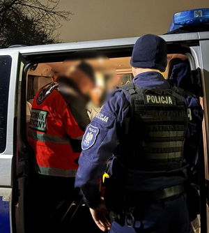 Policjant i ratownik udzielają pomocy starszej kobiecie.