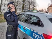 umundurowana Policjantka rozmawiająca przez telefon na tle radiowozu