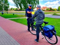 Policjant ruchu drogowego wręcza kamizelkę odblaskową rowerzyście.