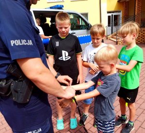 Policjant zakładający kajdanki dziecku w trakcie zabawy.