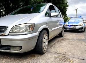 Samochód osobowy i radiowóz stojące na poboczu drogi.