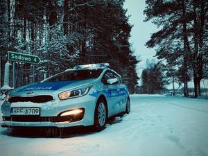 Radiowóz policyjny na zaśnieżonej drodze.