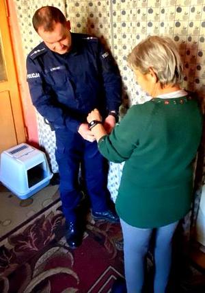policjant  w mundurze zakłada opaskę na rękę seniorki