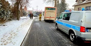 Autobus szkolny, radiowóz i piesi na chodniku.