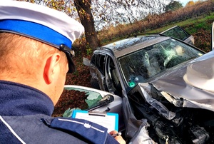 rozbity samochód i policjant wykonujący czynności przy nim