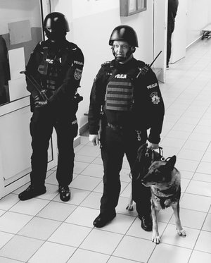 policjant z psem służbowym i drugi policjant z długą bronią