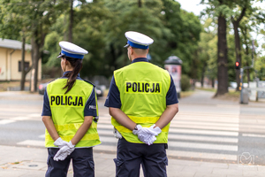 Policjant i policjantka w mundurach przed przejściem dla pieszych.