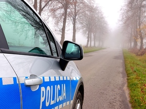 Radiowóz policyjny i w oddali mgła.