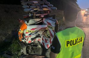 Rozbity samochód służby drogowej oraz policjant w oddali światła aut.