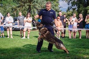 Policjant wykonujący pokaz z psem, w tle widownia.