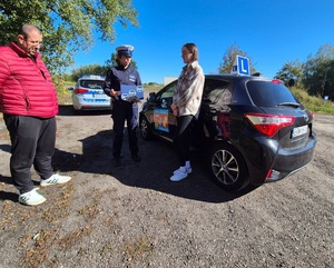 Policjantka z ulotka podczas rozmowy z instruktorem, kursantem i samochód nauki jazdy.