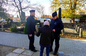 Policjanci rozmawiają z kobieta na cmentarzu.