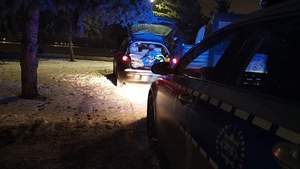 Radiowóz oraz samochód z otwartym bagażnikiem.