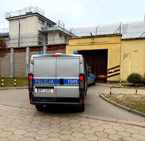 Radiowóz stojący przed bramą zakładu karnego.