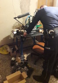 Policjant w trakcie oględzin prasy do nanoszenia napisów na szklane flakony