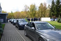 widać dziedziniec komendy policji a na nim kilka radiowozów oraz grupa umundurowanych policjantów