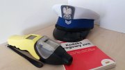 biała policyjna czapka, kodeks i urządzenie do pomiaru stężenia alkoholu w organizmie