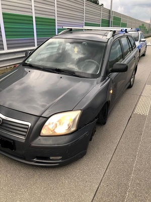 Uszkodzona toyota avensis a za nią radiowóz.