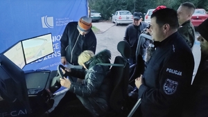 Policjant, seniorka w symulatorze jazdy.