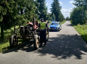 Policjant, ciągnik rolniczy i radiowóz.